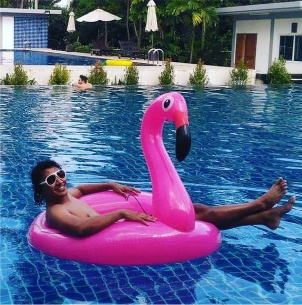 Amar relaxing on a flamingo float in a pool